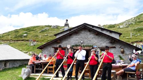 Der Stammkunde Mario Salis und der Gastgeber Christian Bartl beim Dreh von «Mini Beiz, Dini Beiz» auf Alp Muottas.  Empfangen werden alle Gäste vom St. Moritzer Alphorn-Ensemble. Foto: Carolin A. Geist