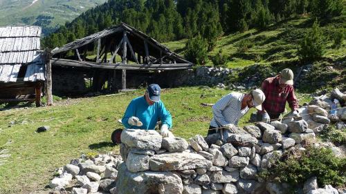 Trais dals homens in acziun, davo els as vezza ils stabels da l’Alp Tamangur Dadora. (fotografia: Flurin Andry)