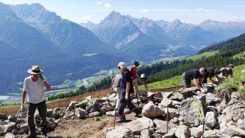 Ils voluntaris vi da la refacziun d’ün mür sech.  (Foto: Sebastian Andermatten / SUS)