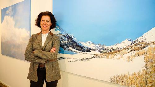 Die Zuozer Künstlerin und Ärztin Esther Rauch posiert in der Galerie La Suosta mit den Bildern «Wolken» und dem neuen Werk «Engadin bis Piz Badile» (vorne). Foto: Jon Duschletta