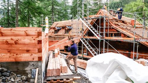 Umbau der Chamonna Cluozza: Links entsteht ein neuer Personal-Schlafturm und rechts wird das Haupthaus mit neuen Lärchenschindeln eingedeckt. Die Eröffnung ist für Juni 2022 geplant. Foto: Jon Duschletta