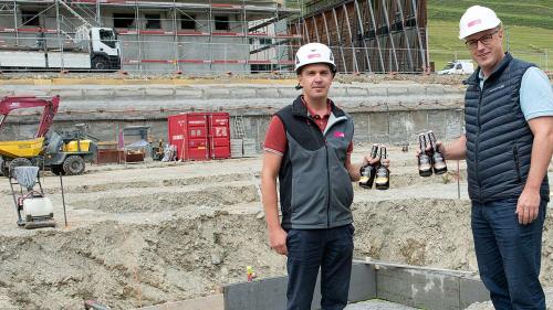 Bauführer Remo Albertin von der Firma Rocca und Hotz Bau (links) und Daniel Käslin mit den Bieren, die anlässlich der Grundsteinlegung beim Gewerbehaus Serlas einbetoniert worden sind. Foto: Reto Stifel